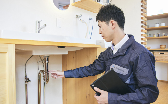 洗面台の給排水管を点検するスタッフ