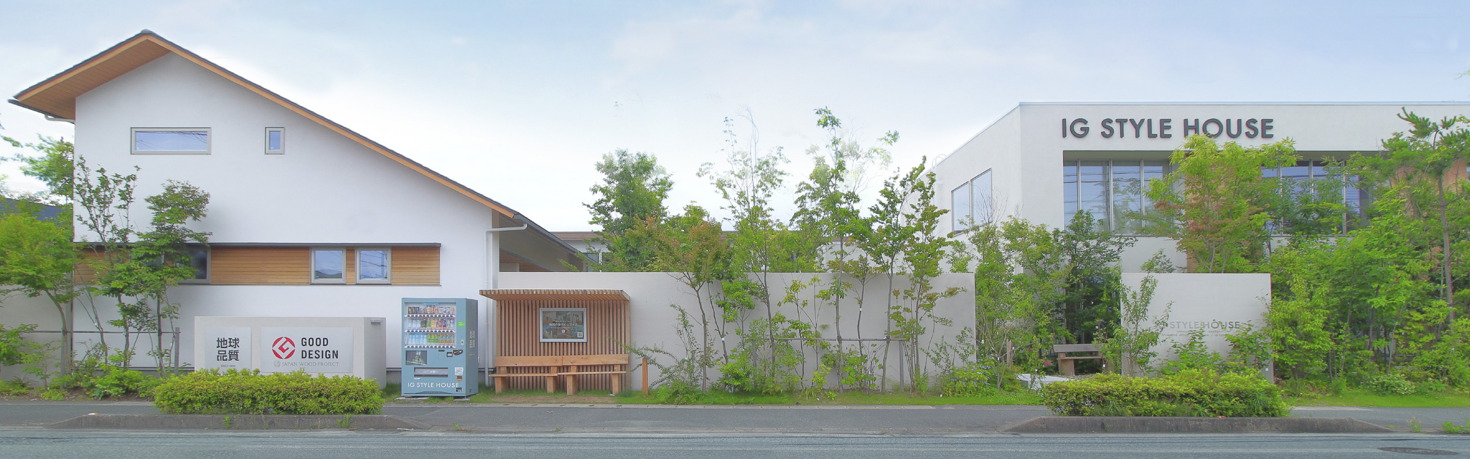 浜松展示場とスタジオの外観。木々に囲まれたモデルハウスとIG STYLE HOUSEの看板がある建物