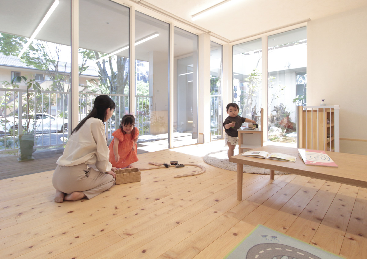 木のおもちゃで遊ぶ子どもたちと、見守るスタッフがいる託児室