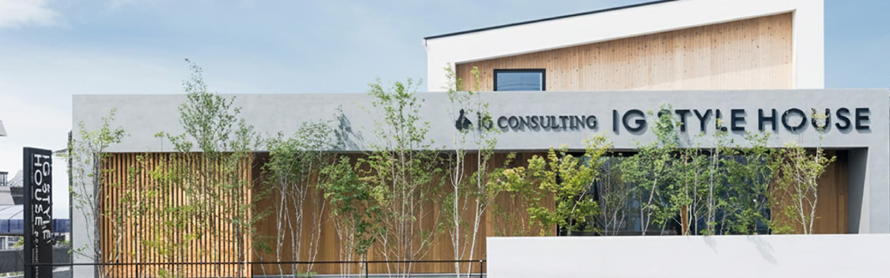 豊橋スタジオの外観。木の格子と植栽、IG STYLE HOUSEの看板がある建物